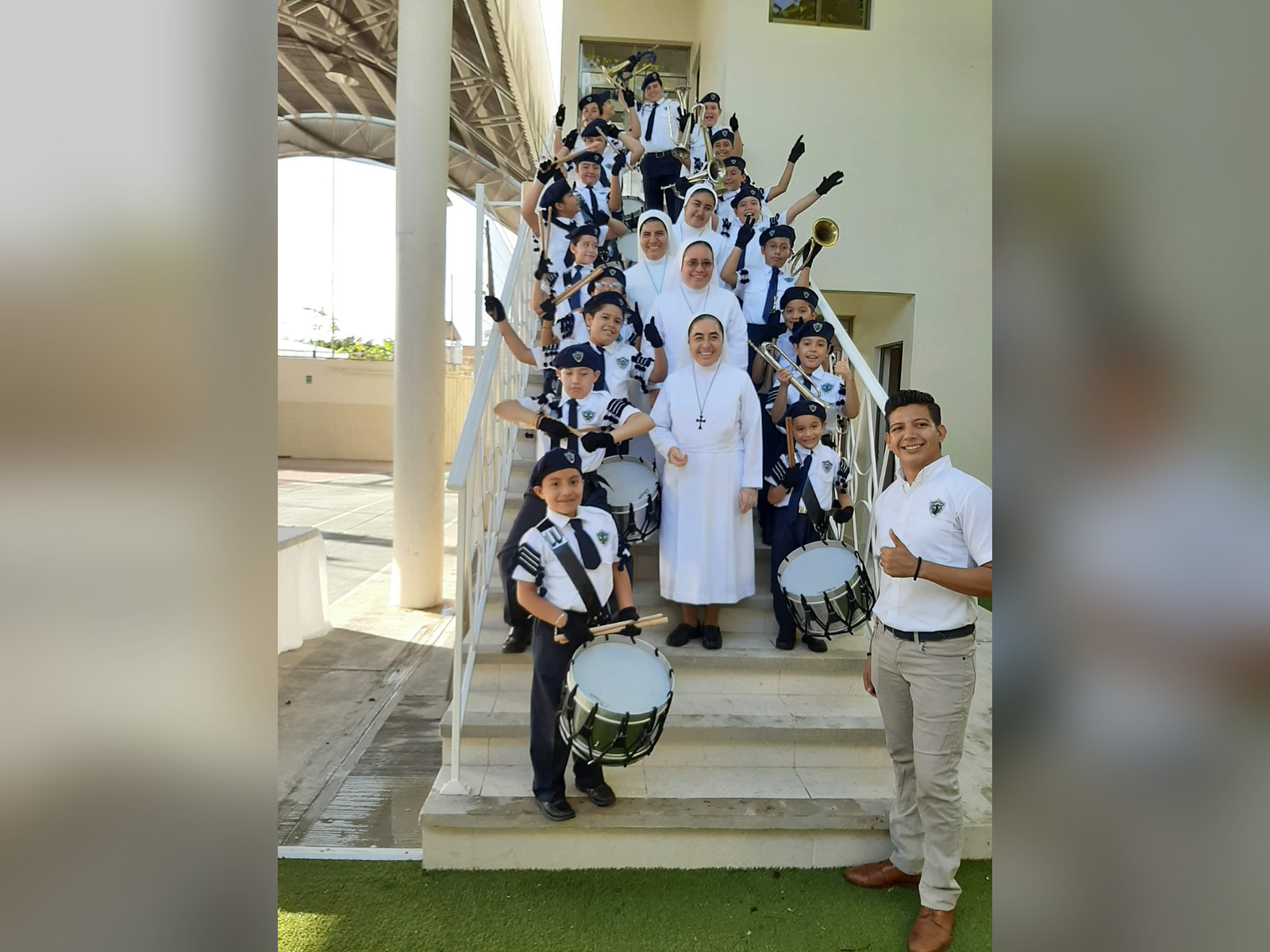 Hermanas y alumnos con tambores en una escalera de la escuela