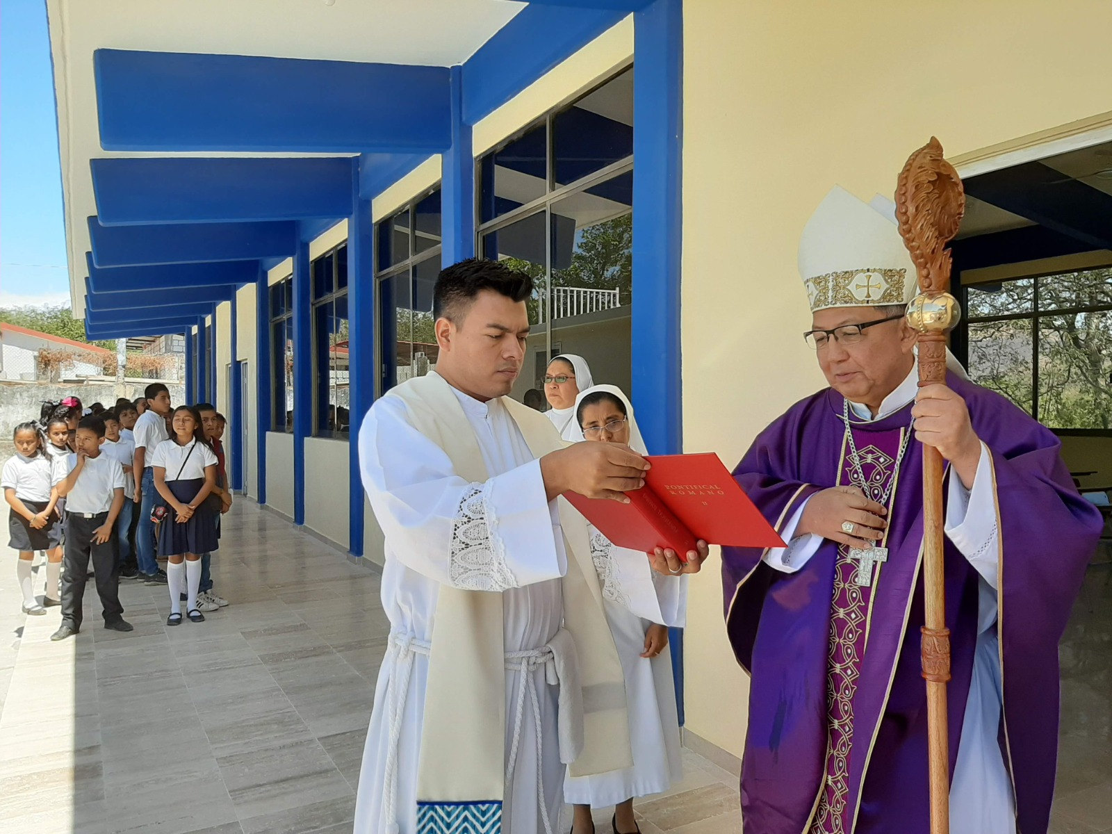 Celebración con un obispo y un sacerdote frente a los alumnos de la escuela