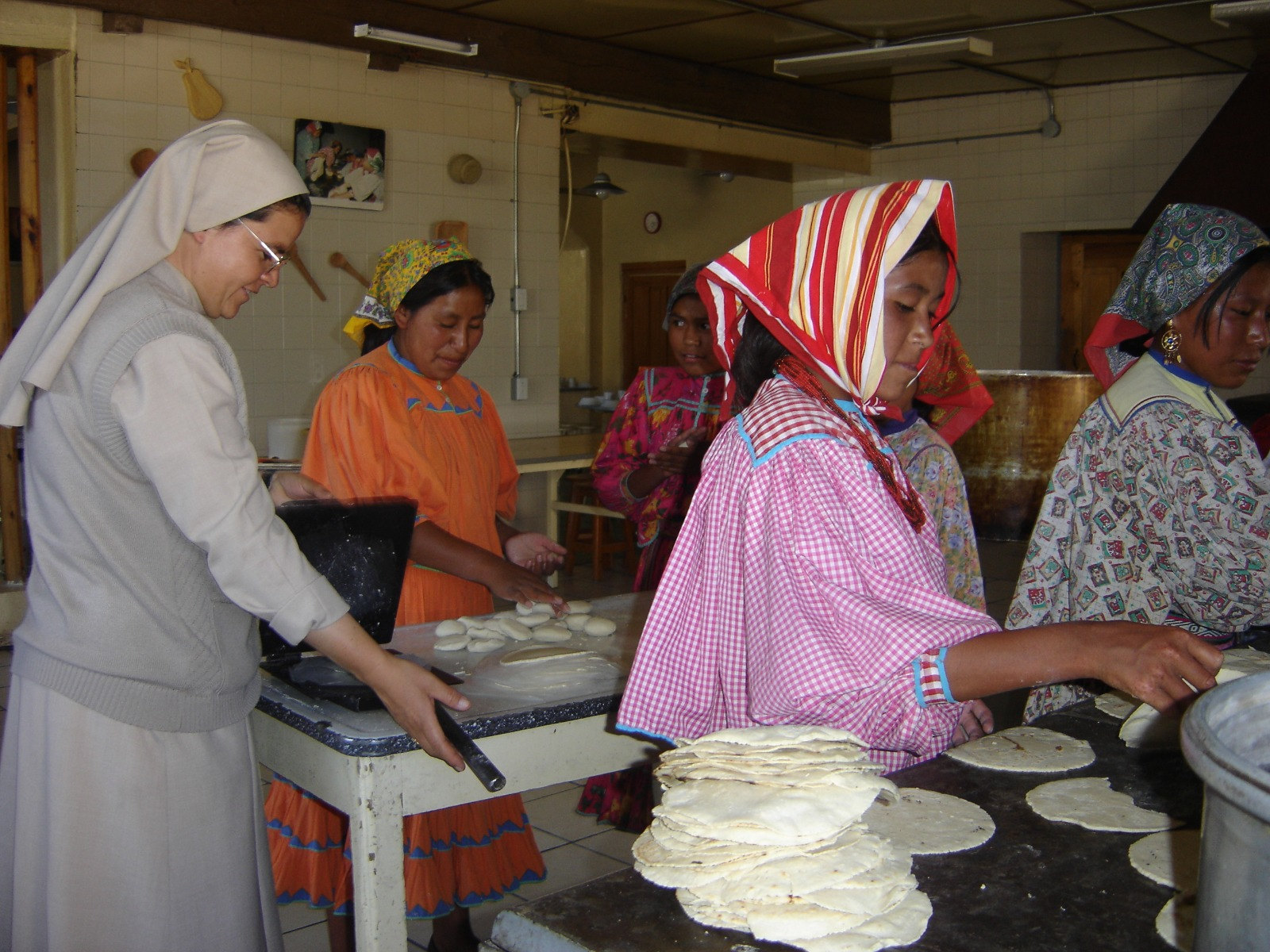 Una hermana prepara tortillas junto con mujeres de la comunidad